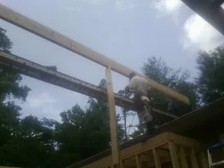Carpenter setting a ridge beam over a new addition frame — Ice Dam Removal by Roofing Brothers in Vassar