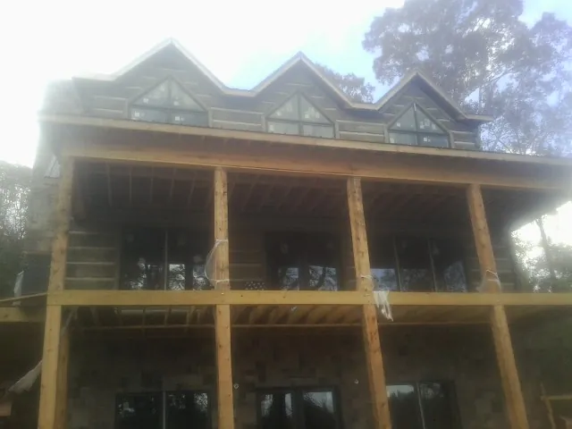 Dormers and porch framing on a large log home under construction — Roof Coating work by our crew in Vassar