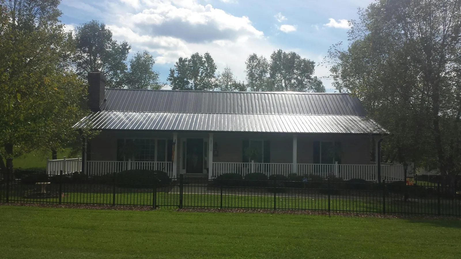 Gray metal roof on a brick ranch with a full width front porch — Gutter Guard Installation work by our crew in Vassar