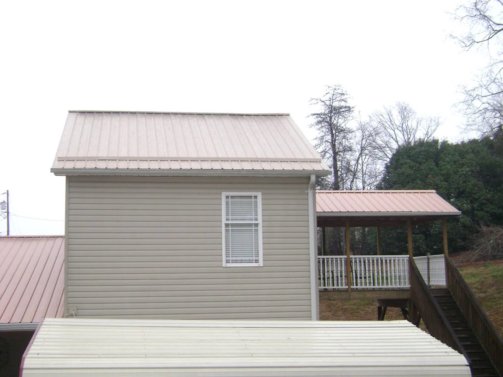 Tan metal roofs on a two story addition and attached porch, from a Roof Replacement job in Vassar