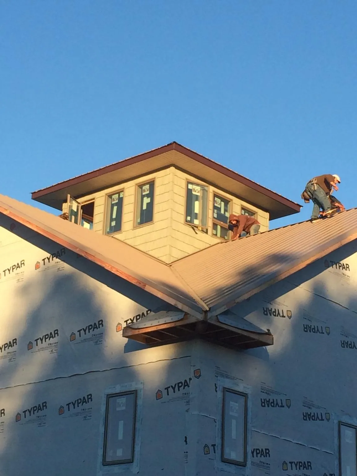 Roofers working around a rooftop cupola on a new metal roof at sunset — Roof Waterproofing in Vassar by Roofing Brothers
